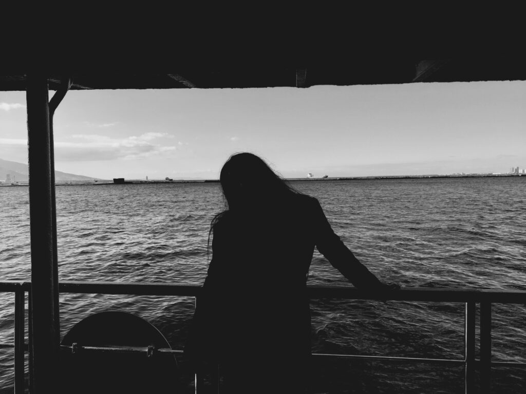 Black and white silhouette of a person standing on a ferry overlooking the Aegean Sea in Türkiye.